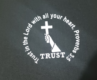 TRUST TRUST IN THE LORD WITH ALL YOUR HEART. PROVERBS 3:5 CIRCLING THE HAND HOLDING THE CROSS WITH THE WORD TRUST BELOW THE HAND. logo